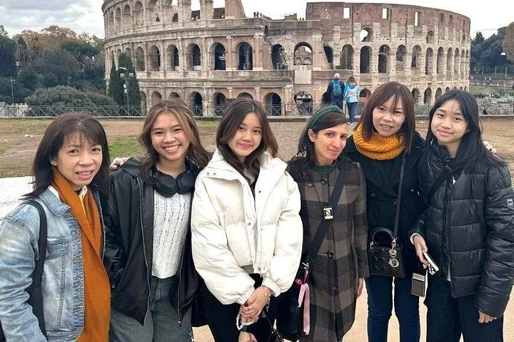 Visitors standing on a public terrace with the Colosseum behind them