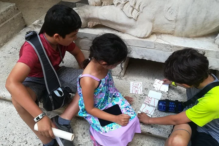 Children working on an activity sheet beside an ancient stone fragment