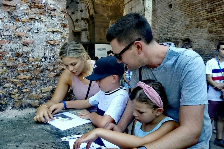 Adults and children completing an activity sheet beside ancient brickwork