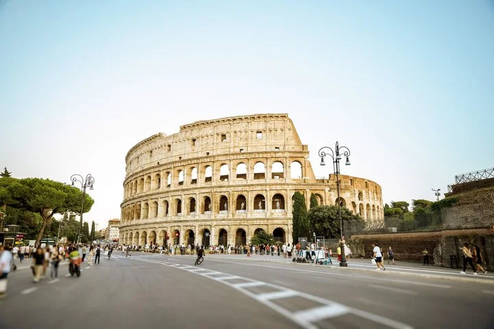 Wide Colosseum exterior with trees and a broad street foreground