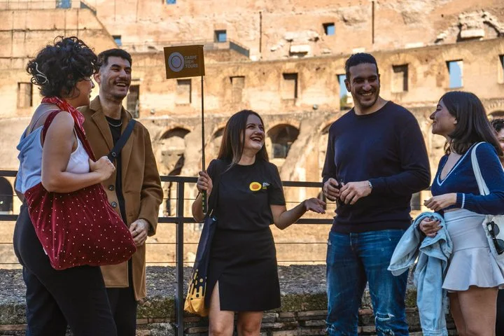 Guide speaking with visitors beside the upper-level Colosseum railing