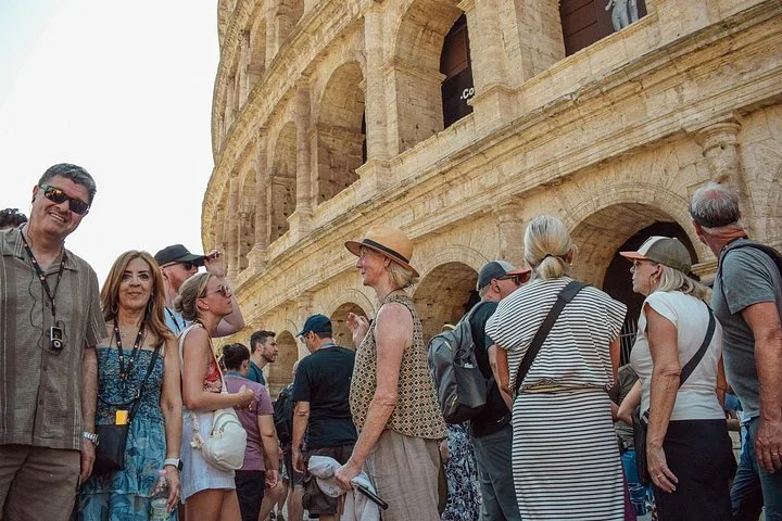 Guide and visitors beside the Colosseum exterior arches