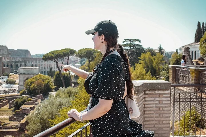 Guide pointing across the Roman Forum toward the Colosseum