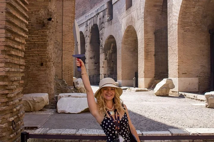 Guide holding a flag in a sunlit Colosseum corridor