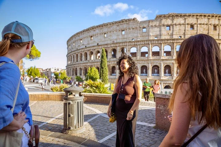 Guide and visitors on a terrace overlooking the Colosseum exterior