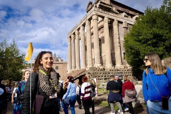 Guide and visitors beside the Temple of Antoninus and Faustina