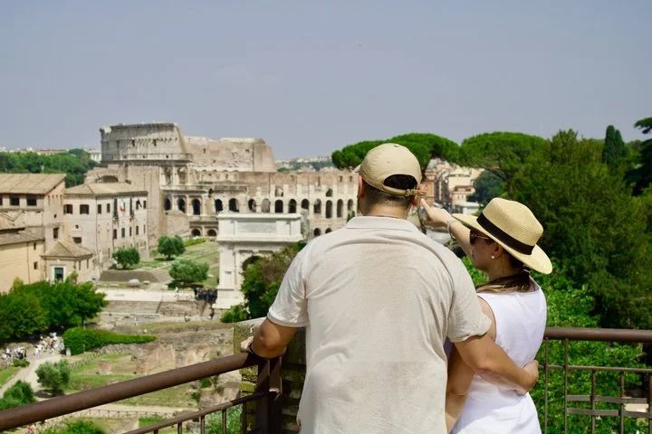 Two visitors overlooking the Roman Forum with the Colosseum in the distance