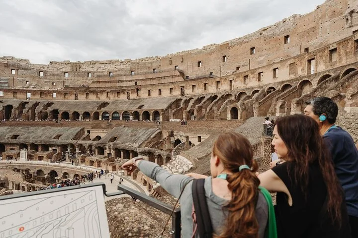 Visitors pointing across the Colosseum from a main-level overlook