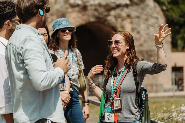 Guide speaking with visitors beside ancient Colosseum masonry