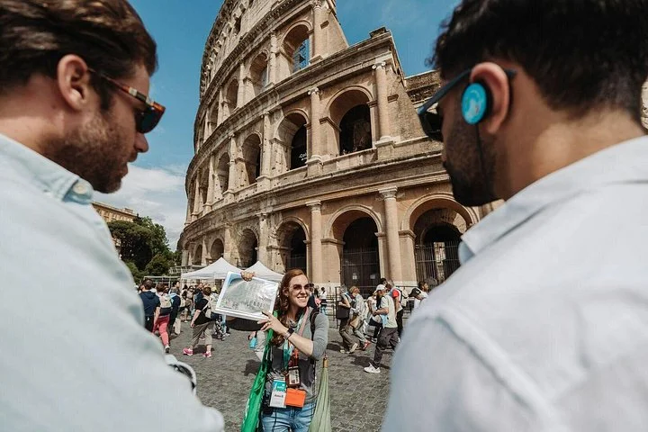 A guide talks with visitors outside the Colosseum.