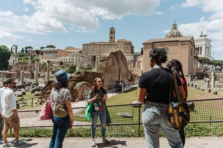 A guide and visitors explore the ruins of the Roman Forum.