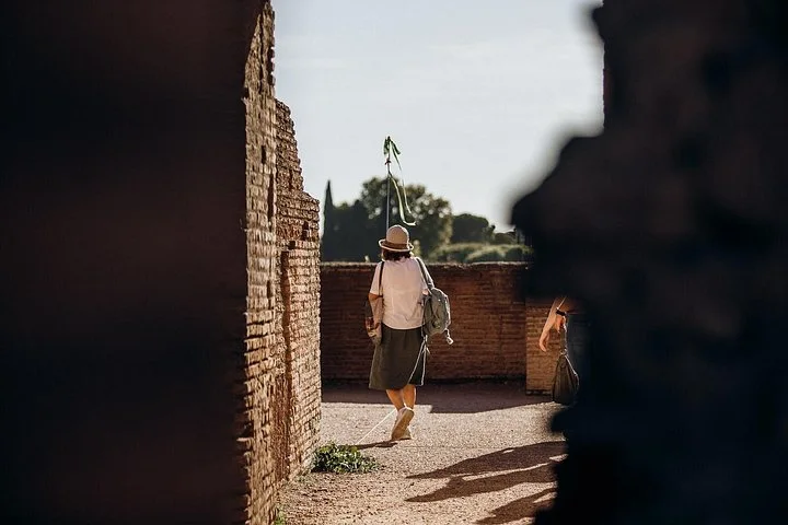 A guide leads the way between ancient brick walls on Palatine Hill.