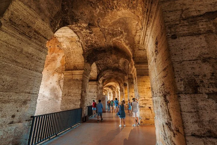 Visitors beneath the long vaulted main Colosseum arcade