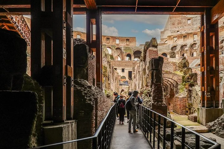 Visitors follow a walkway beneath the Colosseum arena's timber structures.