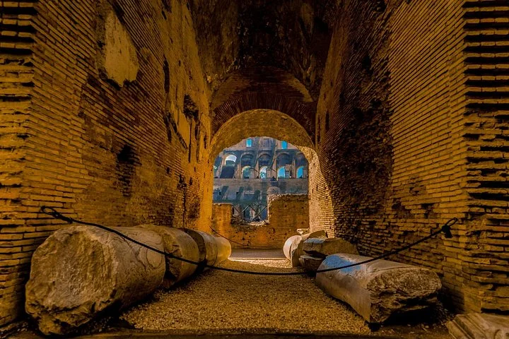 Ancient stone columns lie inside a brick-vaulted Colosseum corridor.