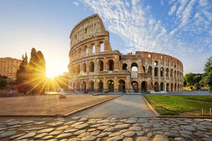 Low golden sunlight shines beside the Colosseum facade.