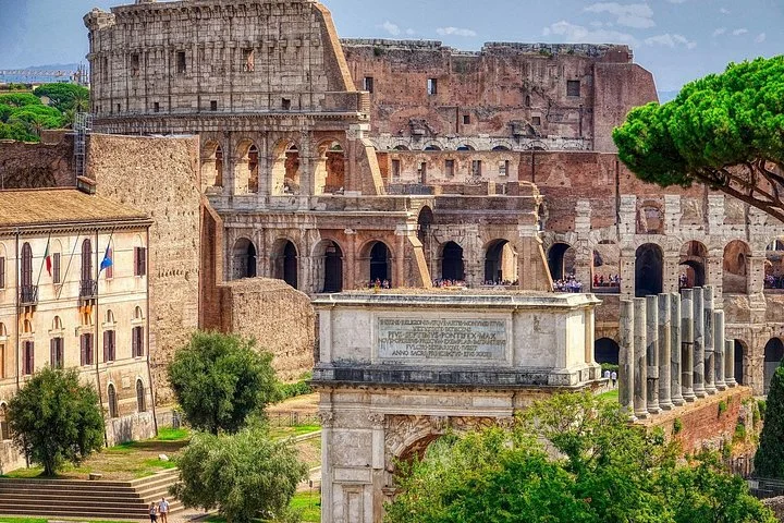 The Arch of Titus and Colosseum appear beyond the ruins and trees of ancient Rome.