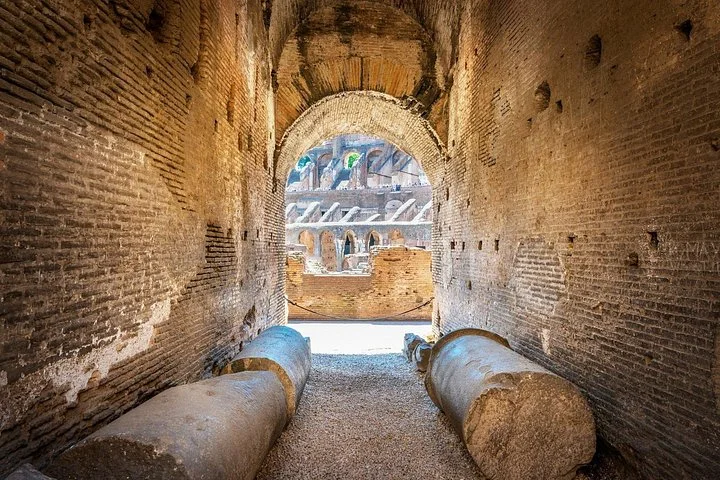 Ancient column fragments rest in a brick-vaulted Colosseum corridor.