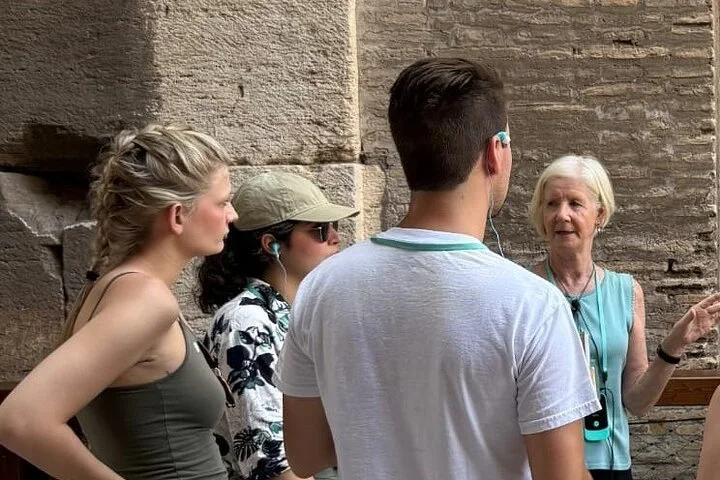 Guide speaking with visitors beside ancient Colosseum masonry