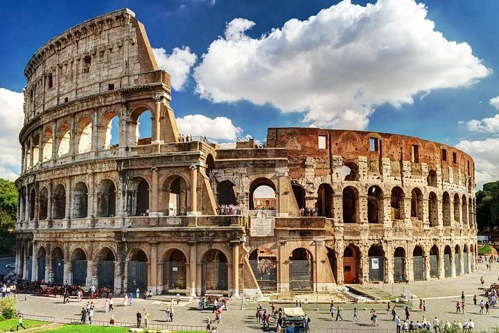 Colosseum exterior beneath blue sky and large white clouds