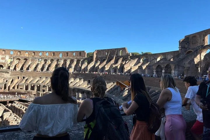 Visitors listening to a guide at a main-level Colosseum overlook