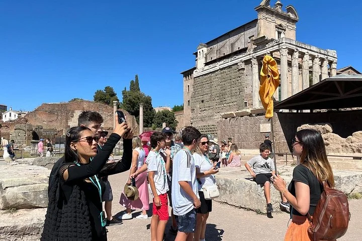 Guide and visitors beside the Temple of Antoninus and Faustina