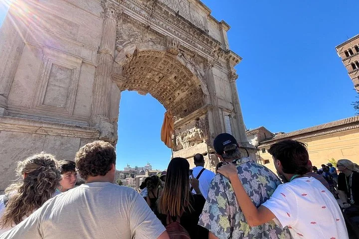 Visitors beneath the sunlit Arch of Titus