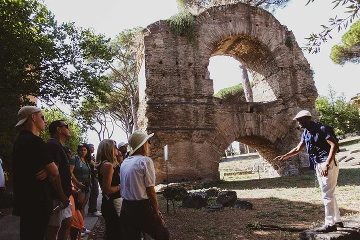 Guide and visitors beside a brick arch on Palatine Hill