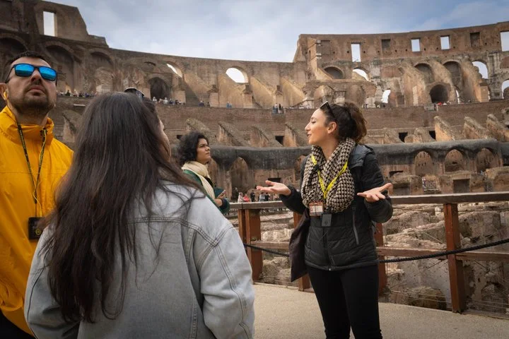 Guide speaking to visitors beside the Colosseum arena platform railing