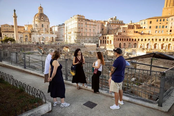Guide and visitors looking across the Roman Forum