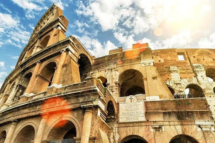 Sunlit Colosseum arches with blue sky and lens flare