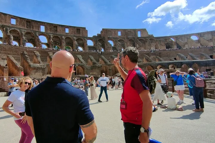 Guide speaking to visitors on the broad Colosseum arena platform
