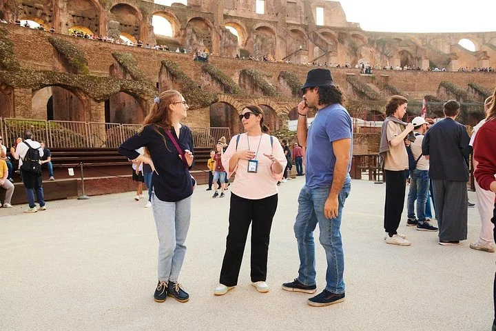 A guide speaks with visitors on the Colosseum arena floor.
