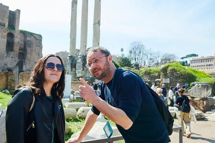 Guide speaking with a visitor beside Roman Forum columns