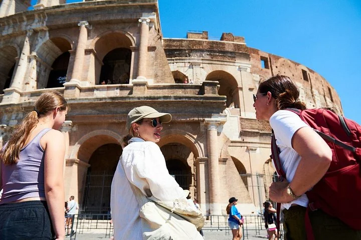 Guide and visitors beside the Colosseum exterior arches