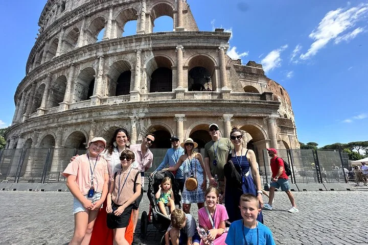 Visitors posing outside the Colosseum beneath blue sky