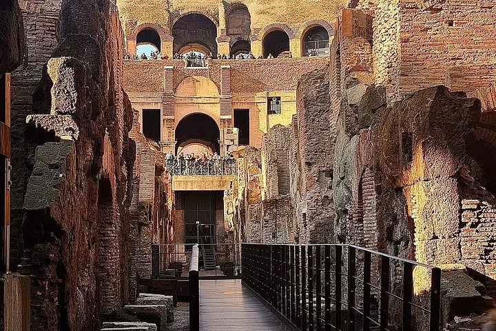 A walkway runs between high stone walls beneath the Colosseum arena.