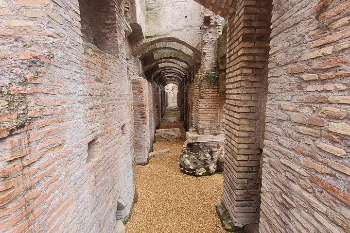 Repeated brick arches recede through a Colosseum underground passage.