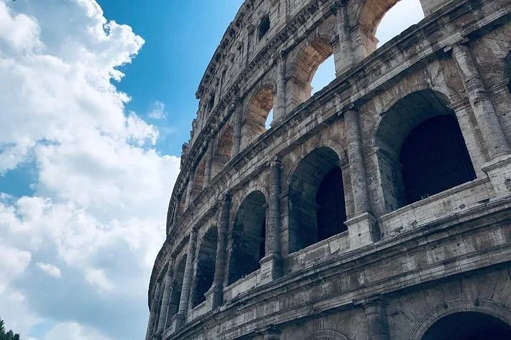 Upward view of Colosseum arches beneath white clouds