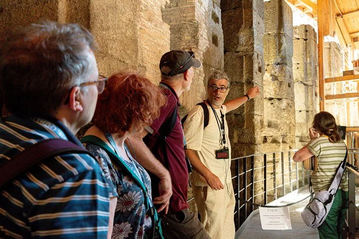 A guide explains the Colosseum's underground stonework beside a timber lift reconstruction.