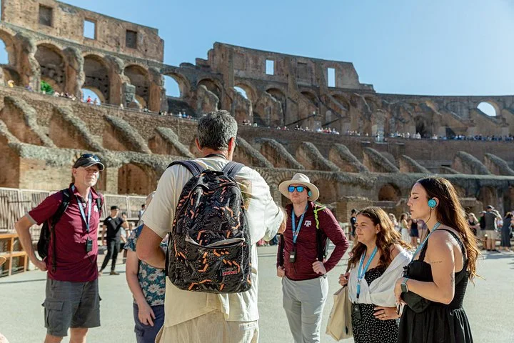 A guide talks with visitors on the Colosseum arena floor.