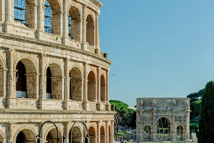 The Colosseum and Arch of Constantine stand beneath a clear sky.