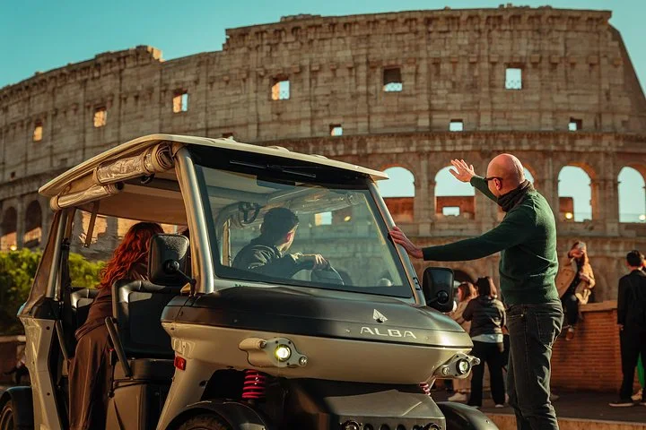 Guide beside a golf cart pointing toward the Colosseum exterior