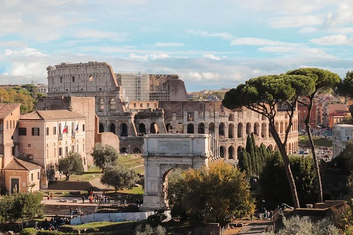 Colosseum exterior seen beyond Forum ruins and umbrella pines