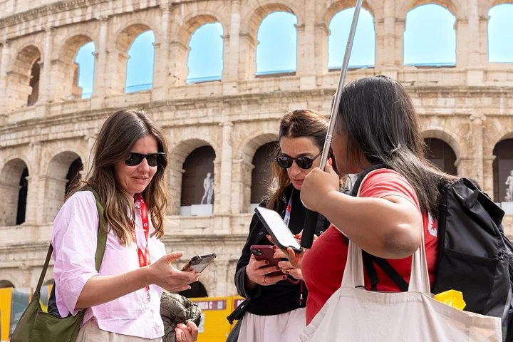 Guide and visitors checking their devices outside the Colosseum