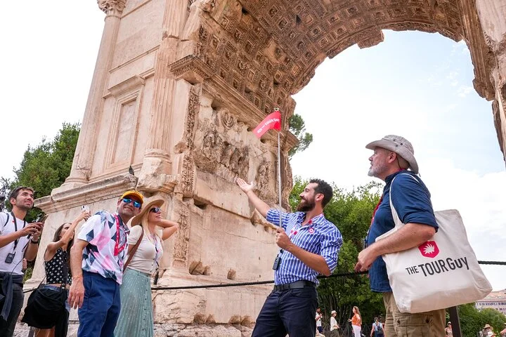 Guide pointing to the carved reliefs beneath the Arch of Titus