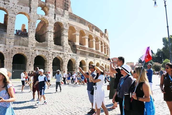 Guide and visitors photographing the Colosseum exterior