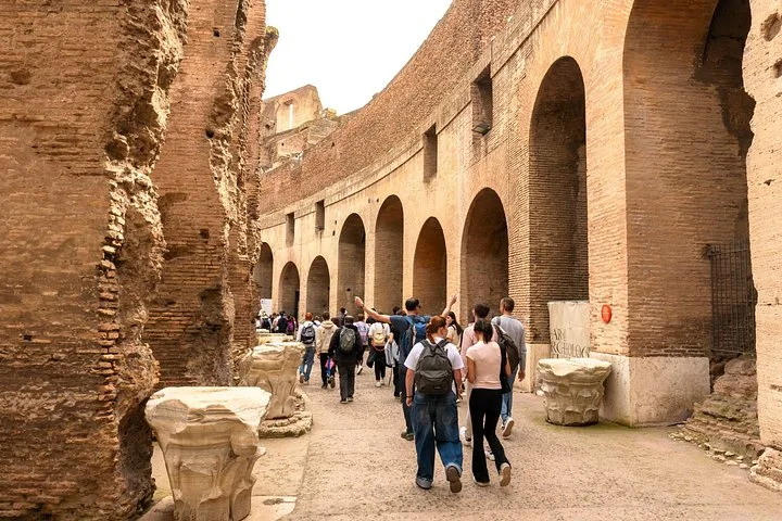 Visitors walking beneath the Colosseum main arcade