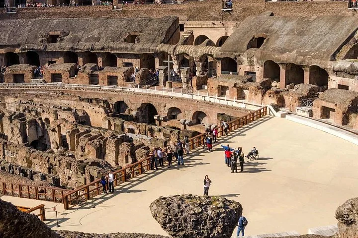 Visitors explore the Colosseum arena platform, viewed from above.