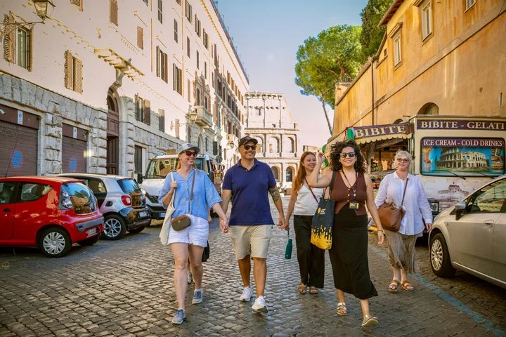 Visitors walking along a cobbled street with the Colosseum behind them